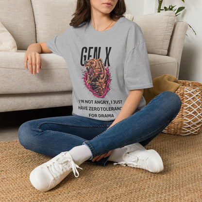 A woman sitting cross-legged on a woven rug in front of a beige sofa, wearing a gray graphic T-shirt featuring a roaring bear illustration with pink and black details, accompanied by the text 'GEN X' and 'PROTECTIVE BY NATURE, CYNICAL BY CHOICE'. 