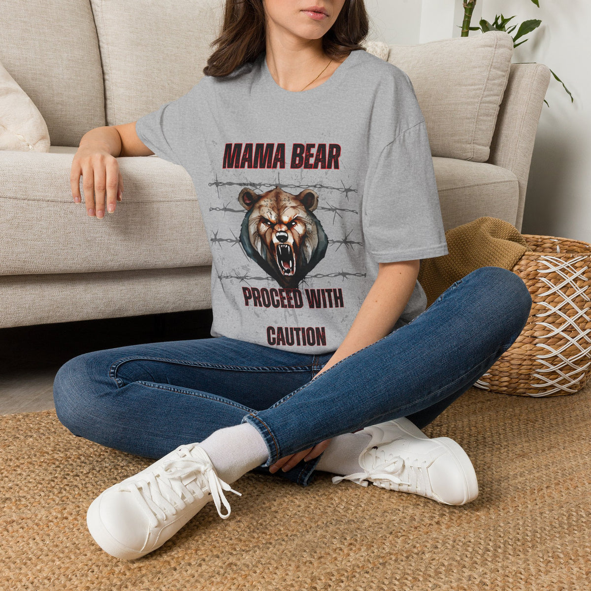 Person wearing a gray t-shirt with a graphic design sitting on a carpeted floor.