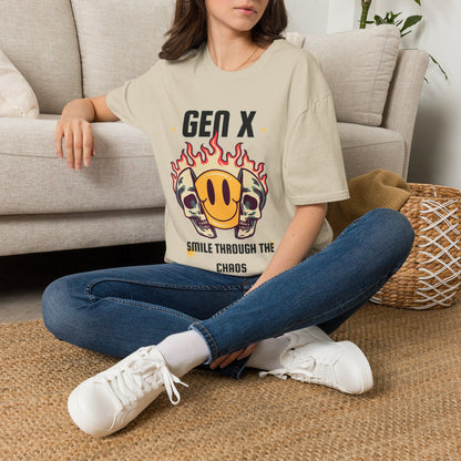 A woman sat on a rug next to the couch wearing a sand graphic t-shirt, featuring a design with two skulls in flames and a yellow smiley face. The text reads 'GEN X SMILE THROUGH THE CHAOS'.