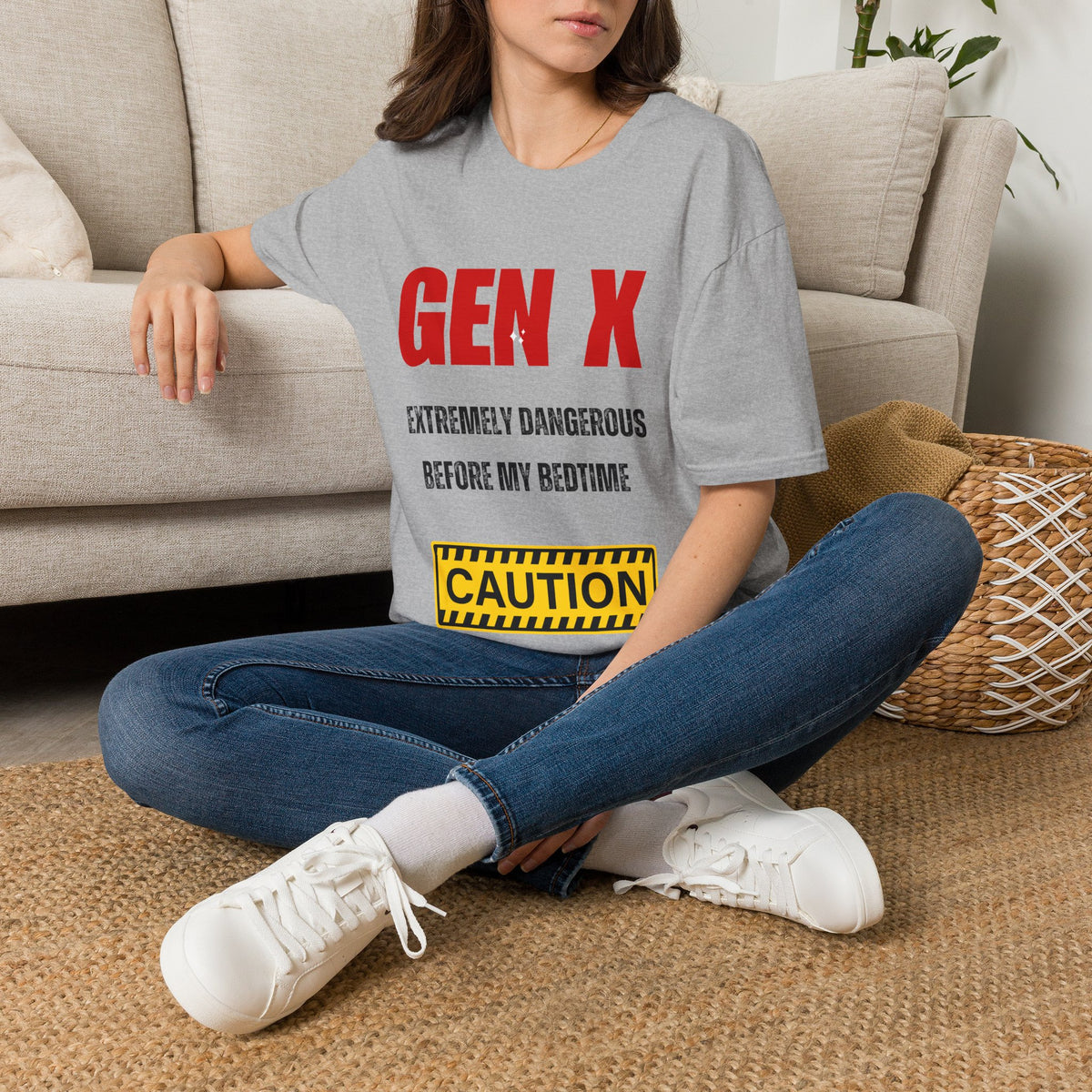 A white graphic t-shirt  featuring the text 'GEN X EXTREMELY DANGEROUS BEFORE MY BEDTIME' in red and black, and a yellow caution-style box. Silver theater masks and a vintage microphone are placed around the shirt,