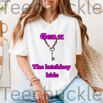 A woman wearing a white graphic t-shirt with a key and chain design and the text 'Gen X The latchkey kids' in pink, paired with light blue jeans in a cozy indoor setting.