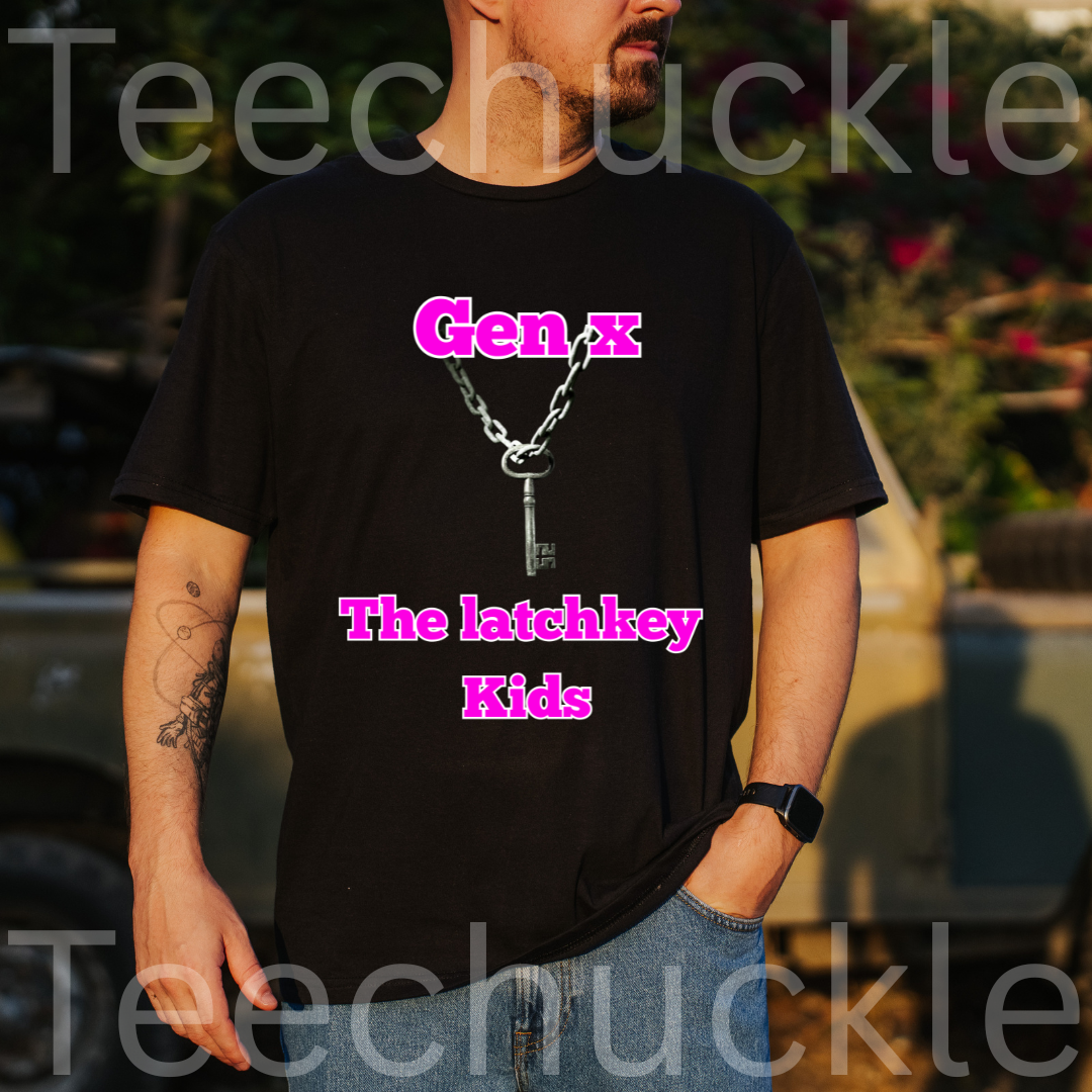 A man wearing a black graphic t-shirt with a silver keychain design and pink text 'Gen X The latchkey Kids', with a blurry outdoor setting in the background