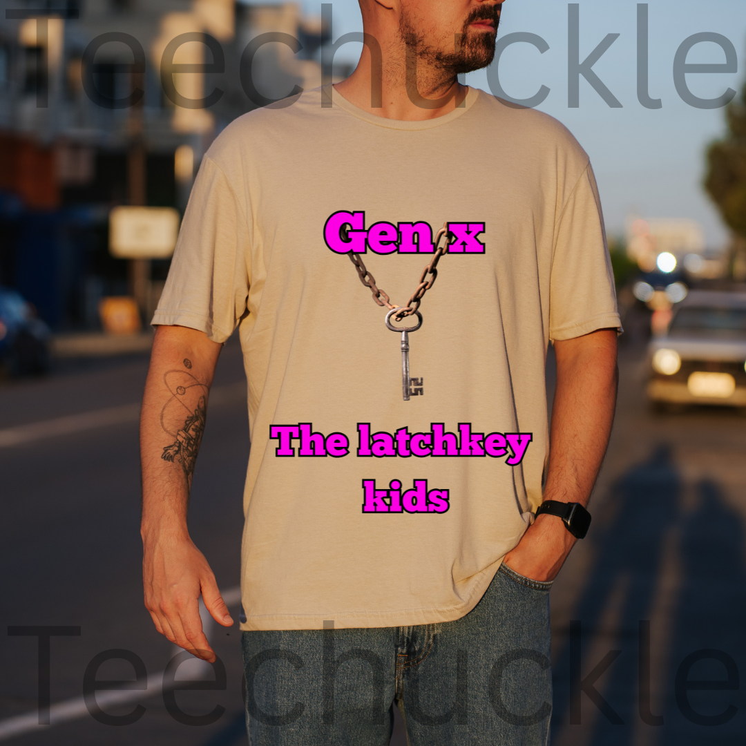 A man wearing a sand graphic t-shirt with a keychain design and the text 'Gen x The latchkey kids' in pink, standing outdoors on a street at sunset.