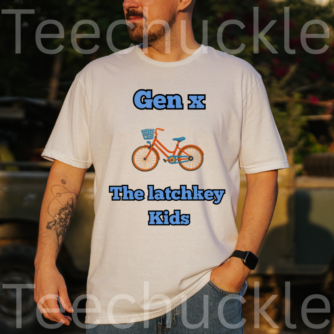 A man wearing a white graphic t-shirt with blue and orange text reading 'Gen x The latchkey Kids' alongside an illustration of a bicycle. The background is a blurred outdoor setting 