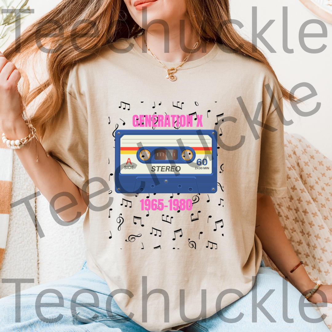 A woman wearing a sand graphic t-shirt featuring a retro 1980s cassette tape design with the text 'GENERATION A 1965-1990' and musical notes, set against a cozy indoor background.