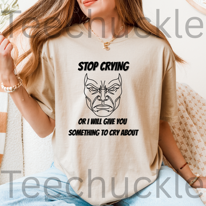 A woman wearing a sand graphic t-shirt with a black printed face and the text 'STOP CRYING OR I WILL GIVE YOU SOMETHING TO CRY ABOUT'.