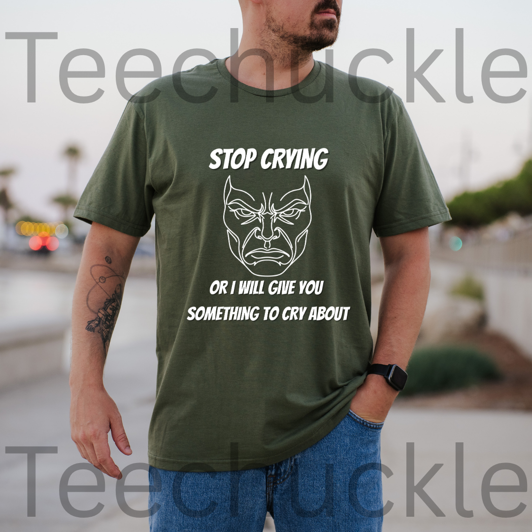 A man wearing a green graphic t-shirt with a white printed angry face and the text 'STOP CRYING OR I WILL GIVE YOU SOMETHING TO CRY ABOUT'.