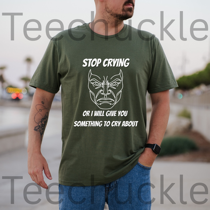 A man wearing a green graphic t-shirt with a white printed angry face and the text 'STOP CRYING OR I WILL GIVE YOU SOMETHING TO CRY ABOUT'.
