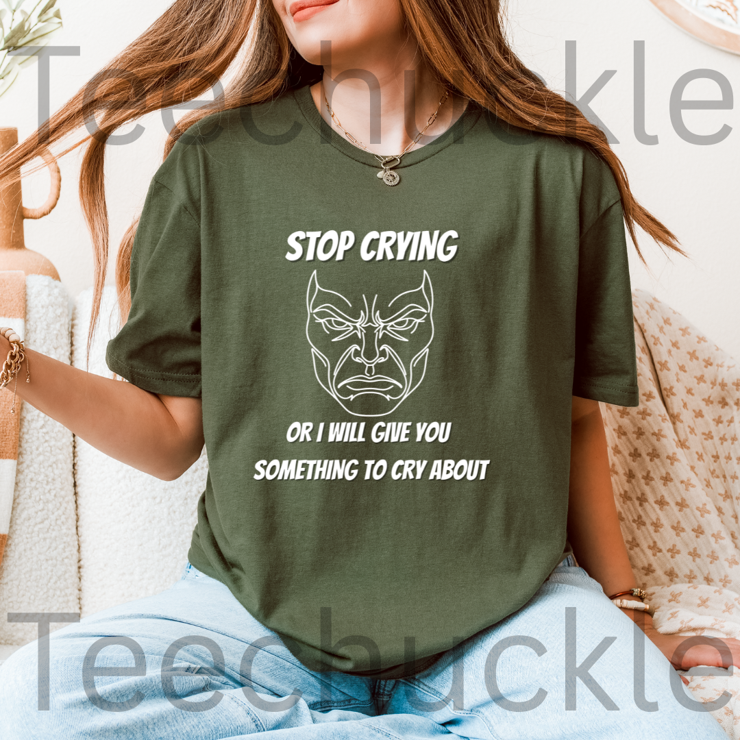 A woman wearing a green graphic t-shirt with a white printed face and the text 'STOP CRYING OR I WILL GIVE YOU SOMETHING TO CRY ABOUT'.