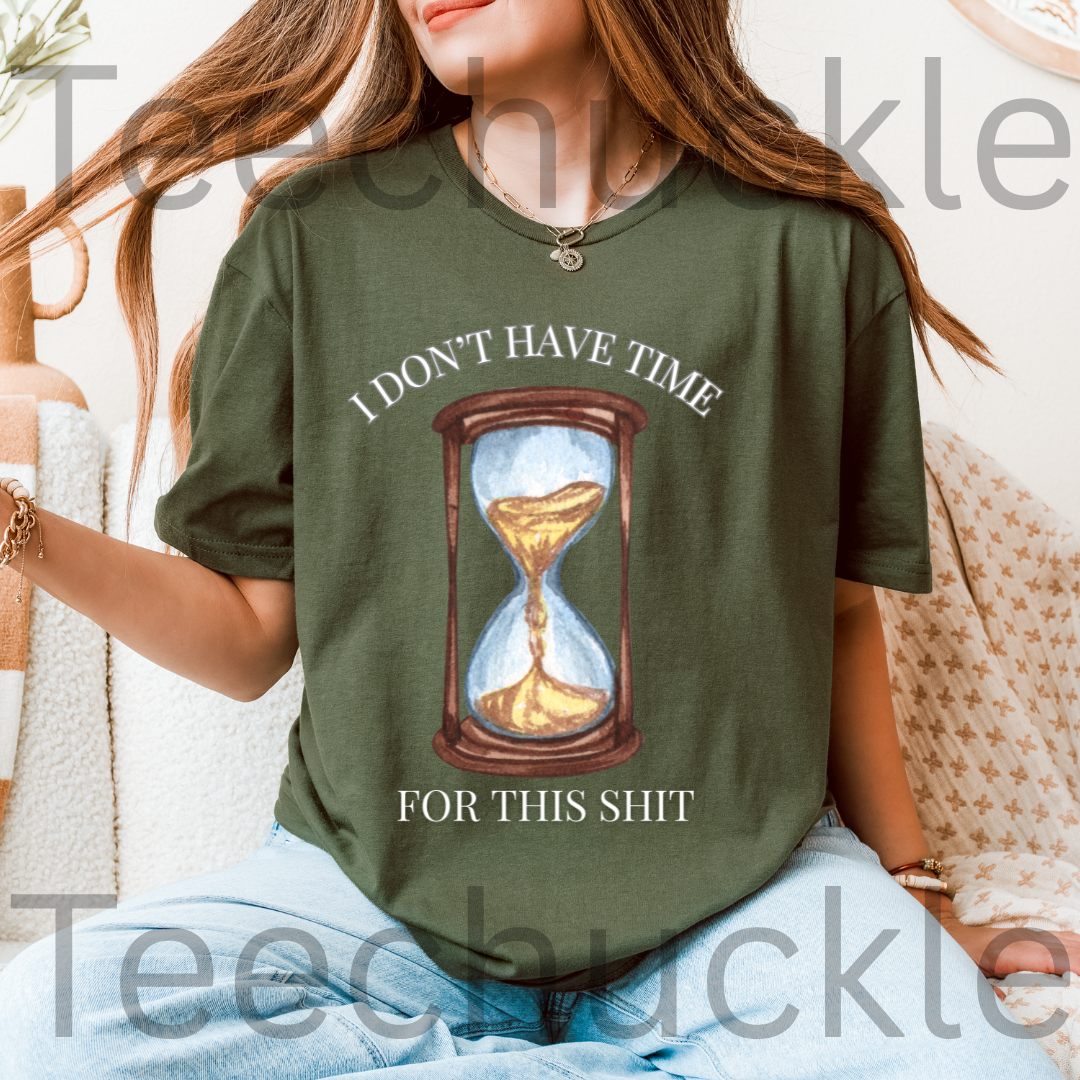 A woman wearing a green graphic t-shirt with a printed hourglass design and the text 'I DON'T HAVE TIME FOR THIS SHIT'.