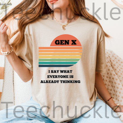 A woman wearing a beige graphic t-shirt with a retro sunset design and the text 'GEN X I SAY WHAT EVERYONE IS ALREADY THINKING'.