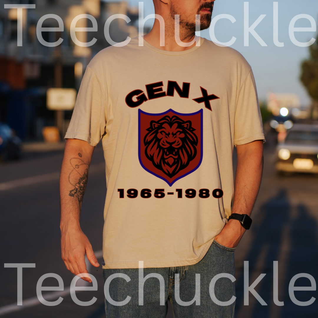 A man wearing a sand graphic t-shirt with a 'GEN X 1965-1980' lion crest design, standing outdoors on a street at sunset. 