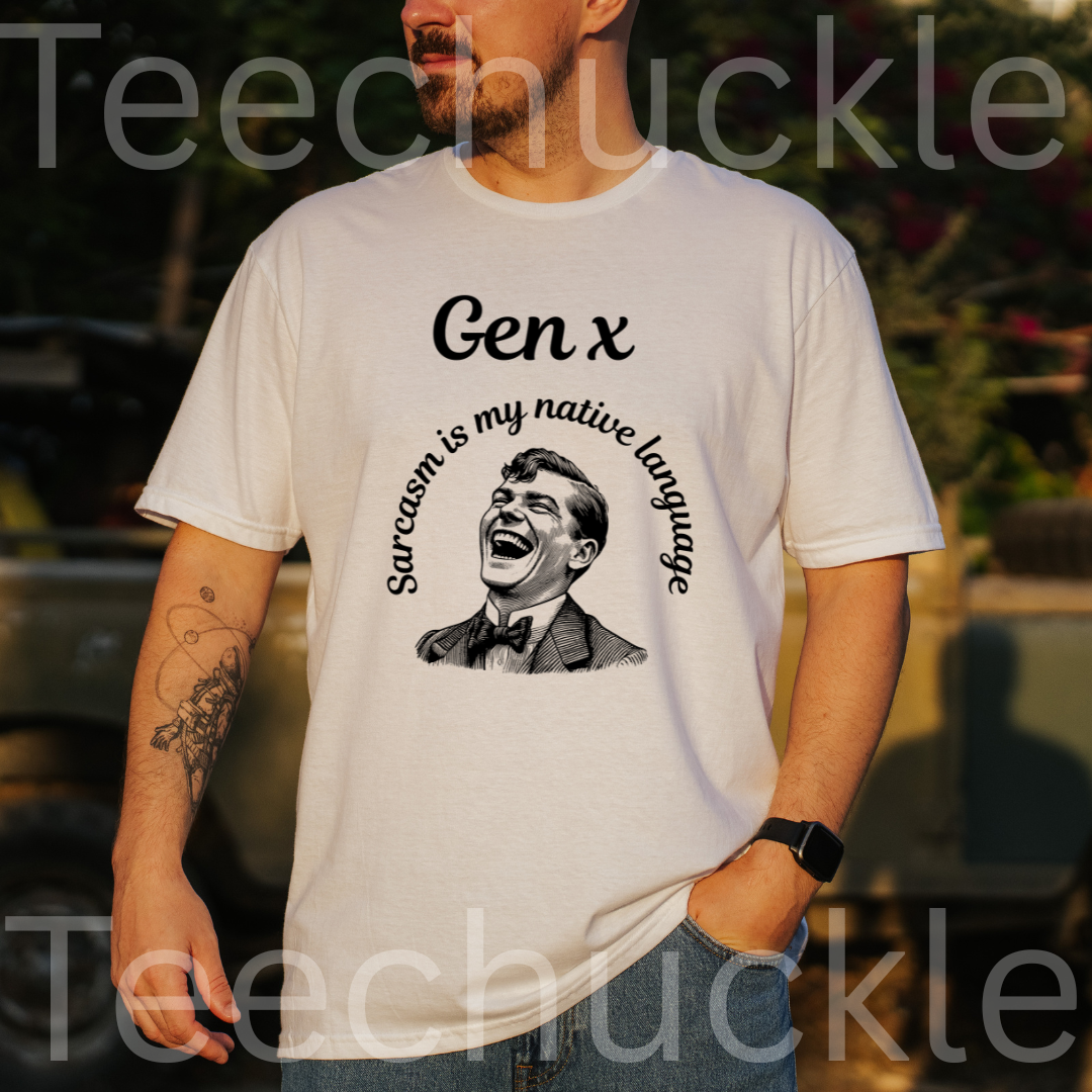 A man wearing a white graphic t-shirt with a black print that reads 'Gen x Sarcasm is my native language' around a laughing man illustration. The background is a blurred outdoor setting 
