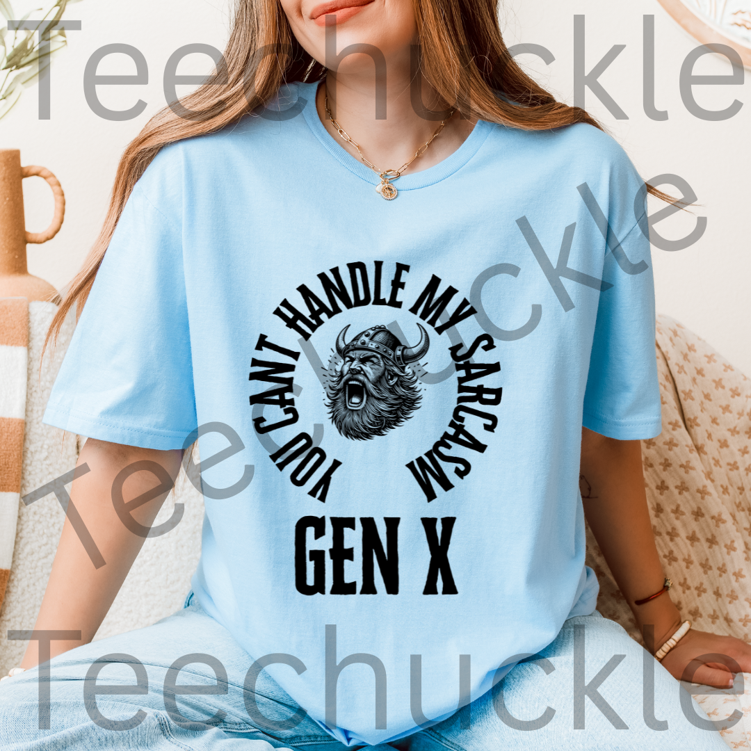 A woman wearing a light blue graphic t-shirt with a black circular design featuring a horned viking and the text 'YOU CAN'T HANDLE MY SARCASM GEN X'. 