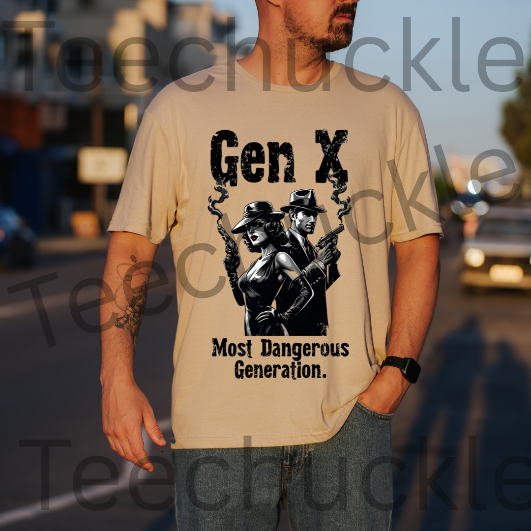A man standing outdoors wearing a sand t-shirt with a graphic of a man and woman standing back to back holding smoking guns and the text "GEN X DANGEROUS GENERATION"