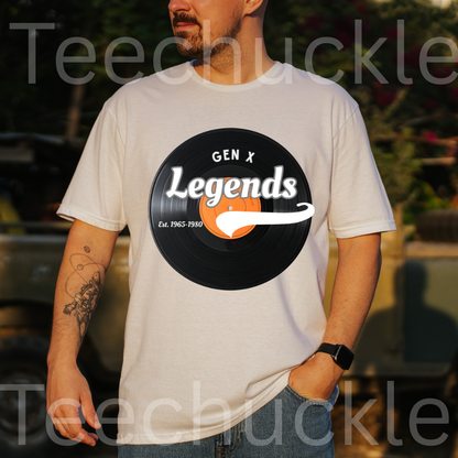 A man stood outdoors wearing a white t-shirt with a vinyl record on it and the text "GEN X LEGENDS EST 1965-1980"