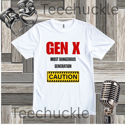 A white short-sleeve graphic T-shirt laid flat on a wood plank background, with red and black text reading 'GEN X MOST DANGEROUS GENERATION' and a yellow caution-style box. Decorative vintage microphones and comedy masks are placed around the shirt