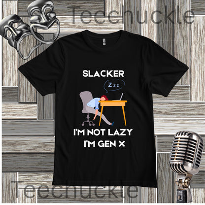 A black graphic t-shirt displayed on a gray wood-paneled background with a vintage microphone and metal headphones. The t-shirt features a cartoon illustration of a person sleeping at a desk with the text 'SLACKER I'M NOT LAZY I'M GEN X'.