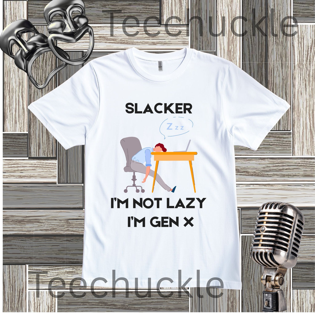 A white graphic t-shirt featuring a cartoon illustration of a person sleeping at a desk with the text 'SLACKER I'M NOT LAZY I'M GEN X'. The t-shirt is displayed on a gray wood-plank background with a vintage microphone, 