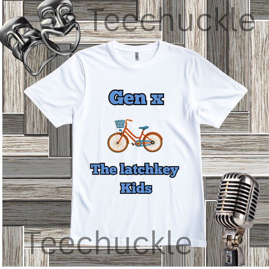 A white graphic t-shirt featuring the text 'Gen x The latchkey Kids' in blue, with an illustration of an orange bicycle in the center. The t-shirt is displayed on a gray wood panel background with vintage-style props, including a silver microphone and a metal object in the corners.