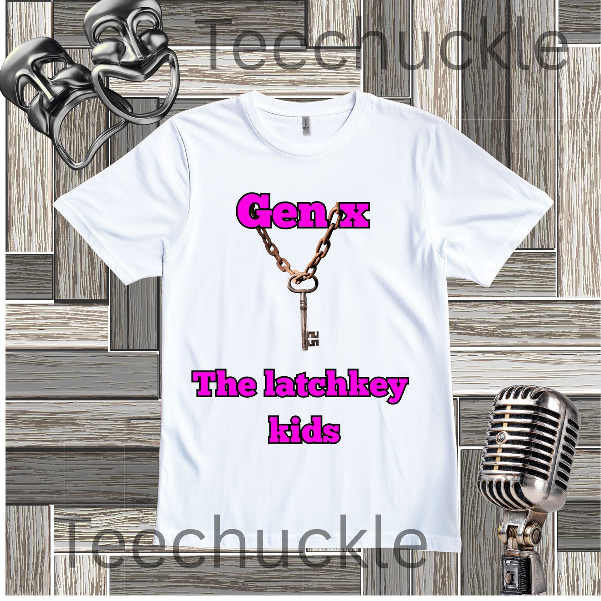 A white short-sleeve graphic t-shirt featuring a vintage key necklace design with the text 'Gen X The latchkey kids' in pink. The shirt is displayed on a gray wood-paneled background with vintage microphone and comedy mask props.