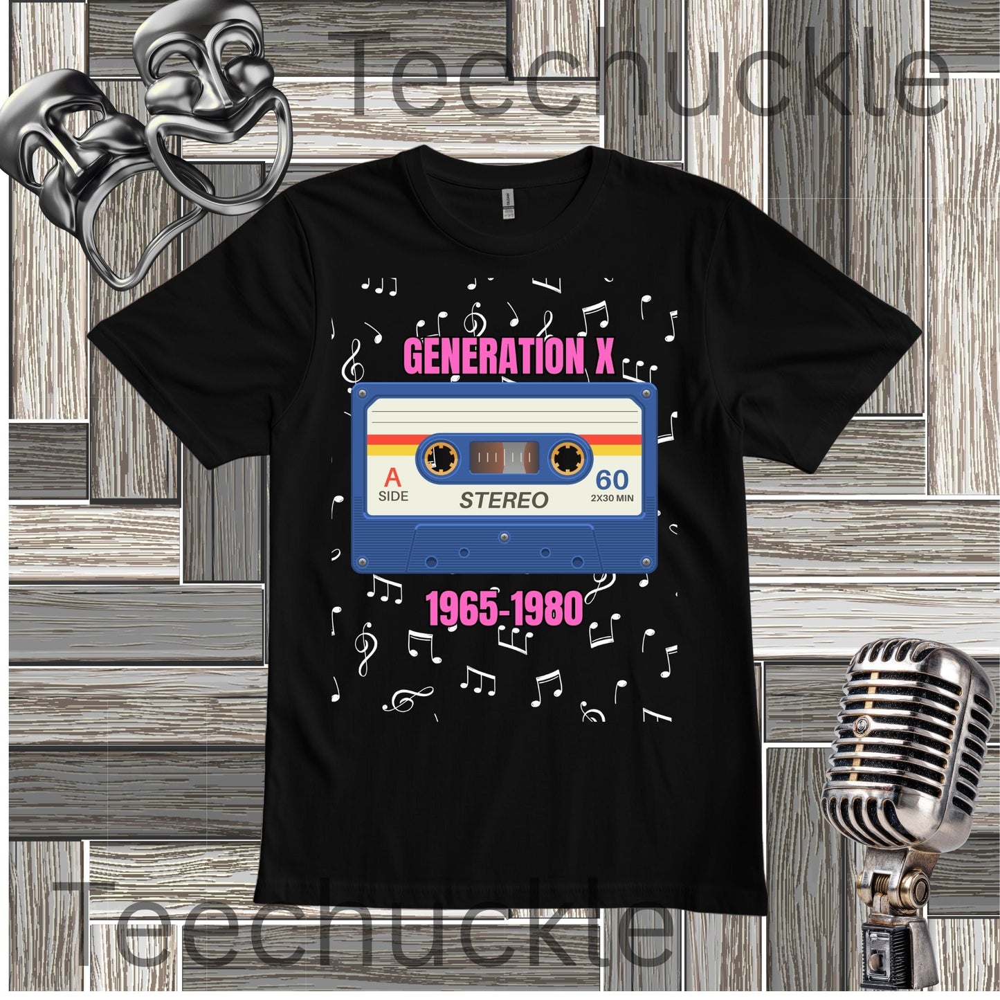 A black short-sleeve graphic T-shirt laid flat on a wood plank background, featuring a retro cassette tape design with the words 'GENERATION X' and '1965-1980' plus white musical notes along with decorative theater masks and a vintage microphone props.