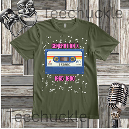 A green graphic t-shirt featuring a retro cassette tape design with the text 'GENERATION X' and '1965-1980' surrounded by musical notes. The t-shirt is displayed on a gray wood-paneled background with decorative vintage props, including a silver theater mask, a retro microphone.