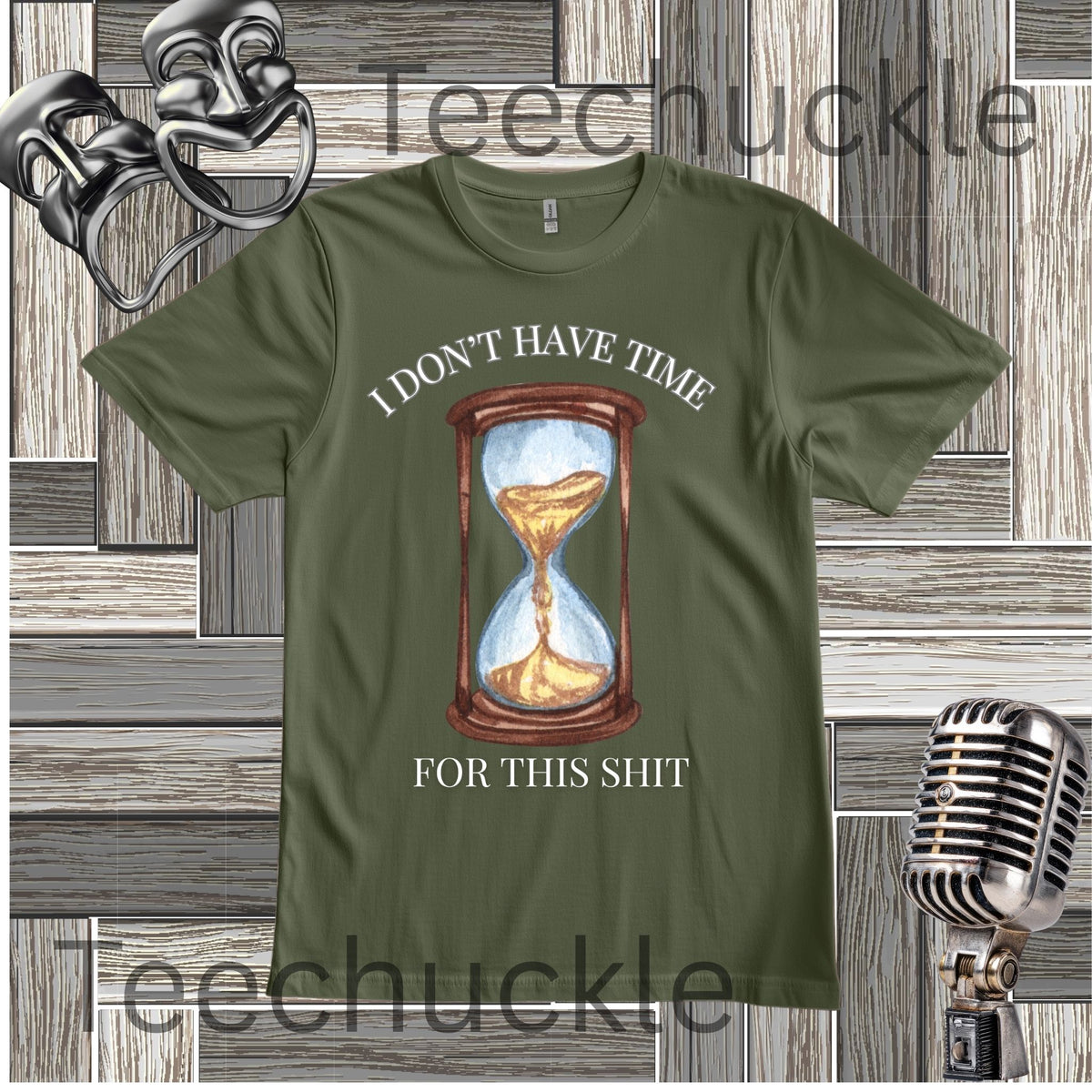 A green graphic t-shirt featuring a vintage-style hourglass illustration with the text 'I DON'T HAVE TIME FOR THIS SHIT' in white. The t-shirt is displayed on a gray wood-paneled background with vintage microphone and comedy theater props.