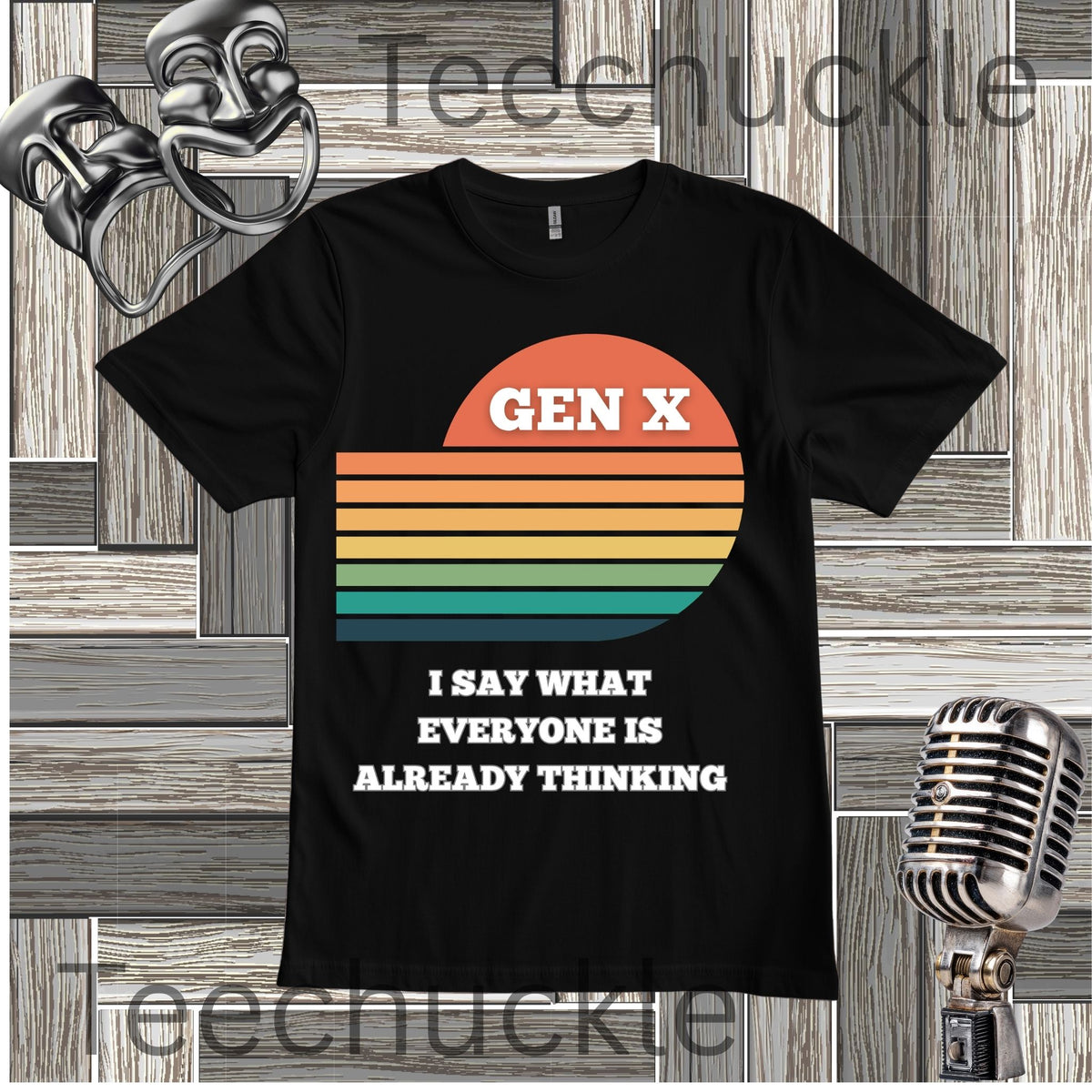 A black short-sleeve graphic T-shirt laid flat on a wood plank background, featuring a retro sunset stripe design in orange, yellow, green, and blue with the text 'GEN X' and 'I SAY WHAT EVERYONE IS ALREADY THINKING' in white. Decorative theater masks and a vintage microphone appear at the corners