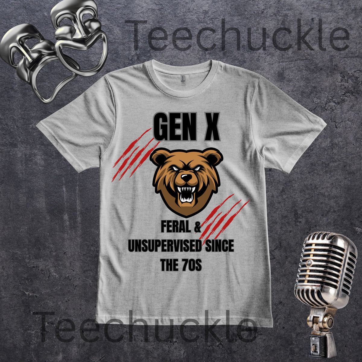 A  gray crewneck t-shirt featuring a 'GEN X' graphic with a grizzly bear head, red claw marks, and the text 'FERAL & UNSUPERVISED SINCE THE 70S'. The shirt is displayed on a dark textured background with vintage-style props including a silver microphone and two metallic comedy masks.