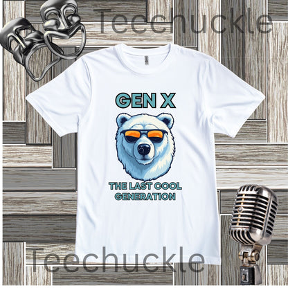 A white short-sleeve graphic T-shirt laid flat on a wood plank background, with black text reading 'Gen x' and 'The last cool generation' a  polar bear illustration. Decorative vintage theater masks and a retro microphone appear around the shirt.