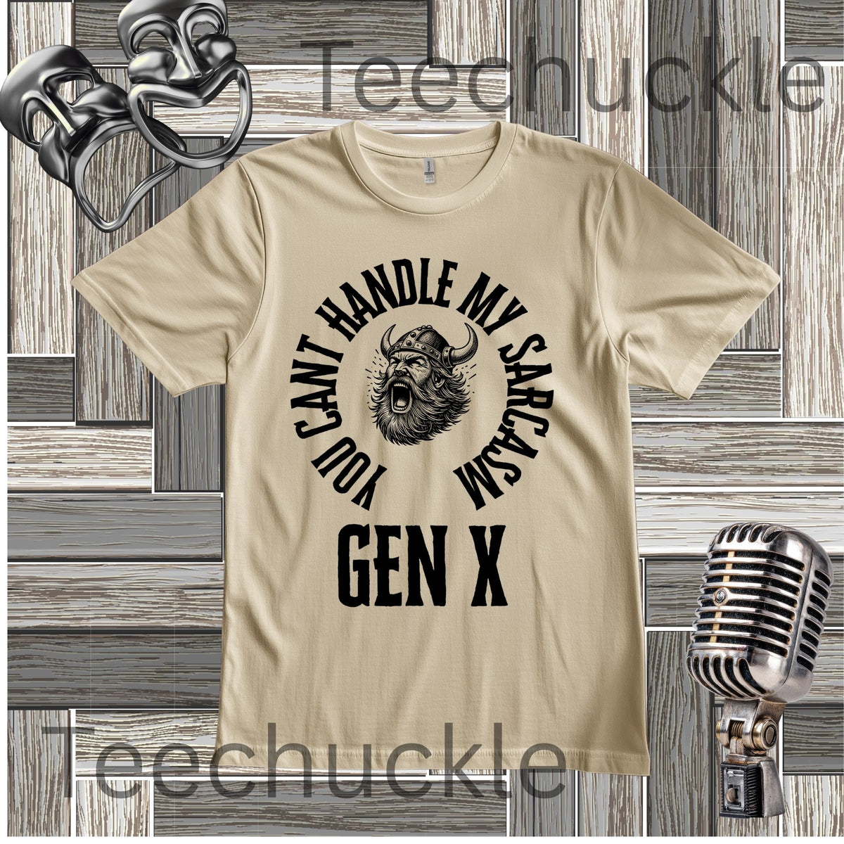 A sand graphic t-shirt featuring a black print of a horned viking head with the text 'YOU CAN'T HANDLE MY SARCASM GEN X' arched around it. The t-shirt is displayed on a gray wood plank background with vintage microphone and headset props