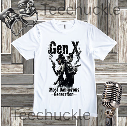 A white short-sleeve graphic t-shirt featuring a black print of a woman and a man holding guns with smoke, and the text 'Gen X Most Dangerous Generation'. The shirt is displayed on a gray wood panel background with a vintage microphone and comedy masks as props.