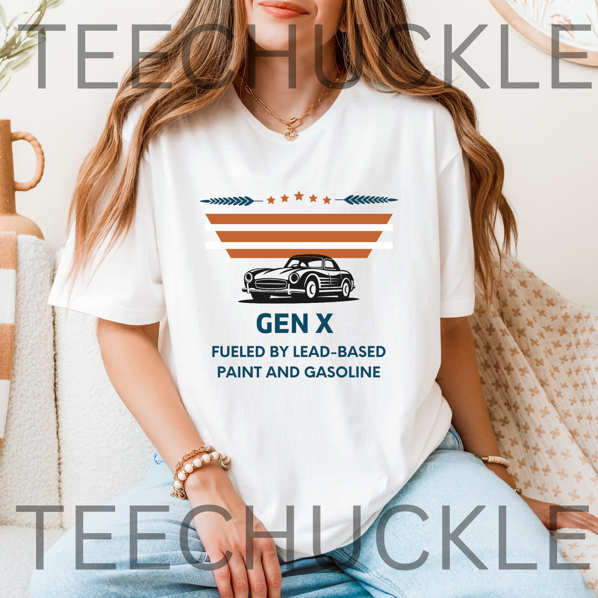 A woman wearing a white graphic T-shirt with a vintage-style car and the text 'GEN X FUELED BY LEAD-BASED PAINT AND GASOLINE', and the model is seated indoors against a light neutral background.
