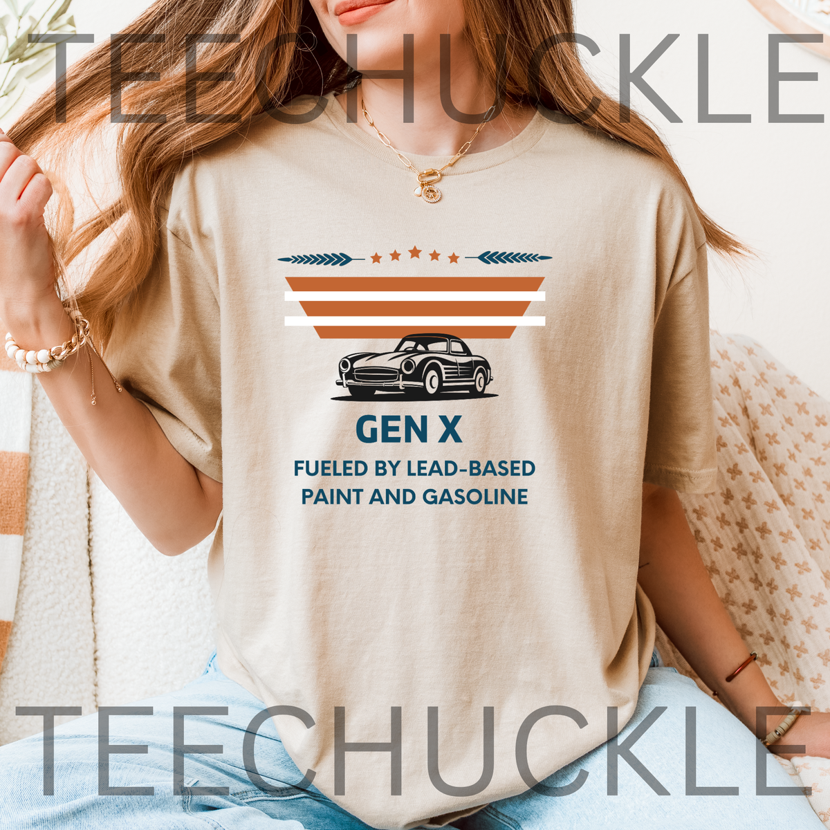 A woman wearing a sand graphic t-shirt with a vintage-style car and text that reads 'GEN X FUELED BY LEAD-BASED PAINT AND GASOLINE'.