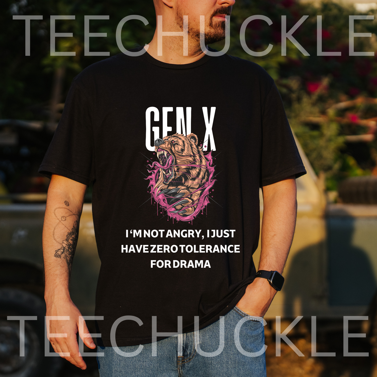 A man wearing a black graphic t-shirt with a bear illustration and the text 'GEN X I'M NOT ANGRY, I JUST HAVE ZERO TOLERANCE FOR DRAMA', and the background shows an outdoor setting with a vehicle.