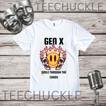 A white graphic t-shirt displayed on a rustic wood background, featuring a design with two skulls in flames and a yellow smiley face. The text reads 'GEN X SMILE THROUGH THE CHAOS', in the corners are comedy masks and a vintage microphone.