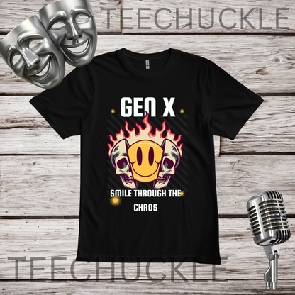 A black short-sleeve graphic T-shirt laid flat on a rustic wood background, with two silver theater masks, a vintage microphone. The shirt graphic reads “GEN X SMILE THROUGH THE CHAOS” above and below a smiling face inside a skull with flames around it.