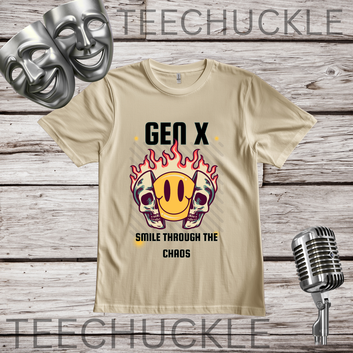 A sand graphic t-shirt displayed on a rustic wood background, featuring a 'Gen X Smile Through The Chaos' design with a yellow smiley face, red flames, and skulls. The shirt is styled with silver theater masks, a vintage microphone