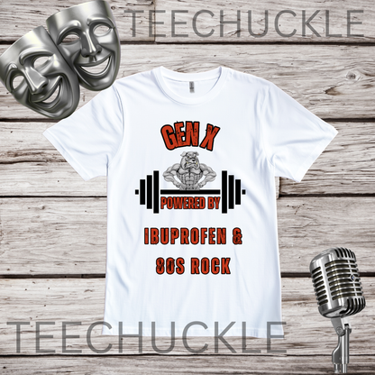 A white graphic t-shirt displayed on a rustic wood background, featuring a design with two silver comedy masks, a vintage microphone, and the text 'GEN X POWERED BY IBUPROFEN & 80S ROCK' with a muscular bulldog cartoon character and barbell graphic. 
