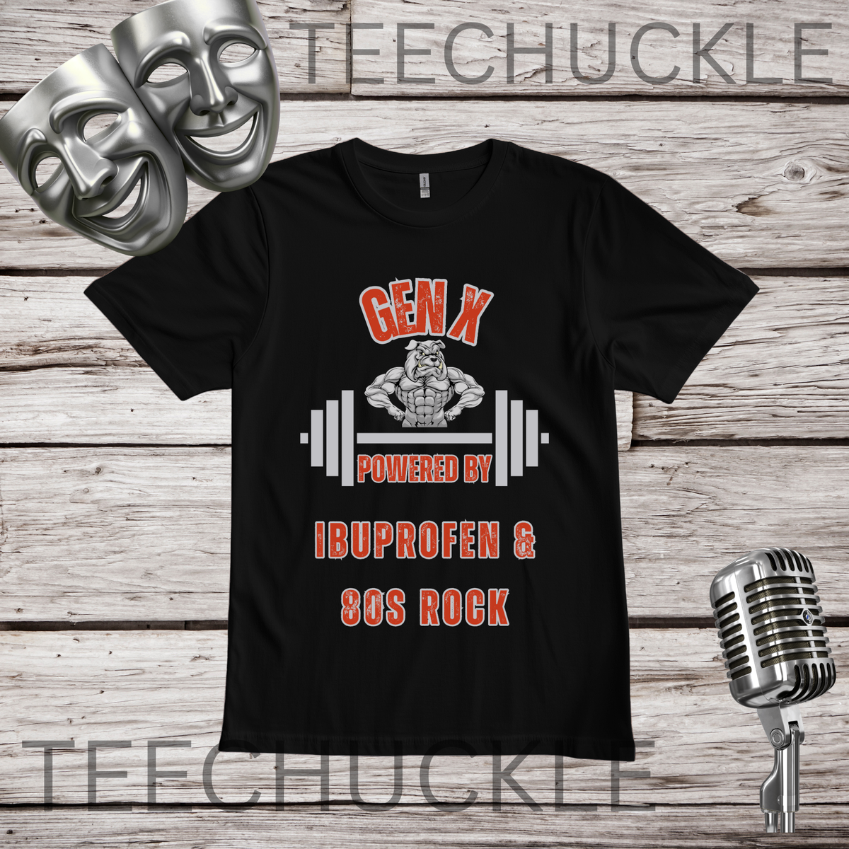 A black graphic t-shirt displayed on a rustic wood background, featuring a design with two silver comedy masks, a vintage microphone, and the text 'GEN X POWERED BY IBUPROFEN & 80S ROCK' with a muscular bulldog cartoon character and barbell graphic. 