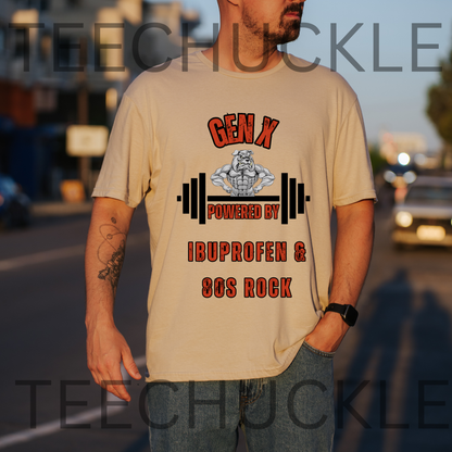 A man wearing a sand graphic t-shirt with a 'Gen X Powered by Ibuprofen & 80s Rock' design, standing outdoors on a street at sunset. 