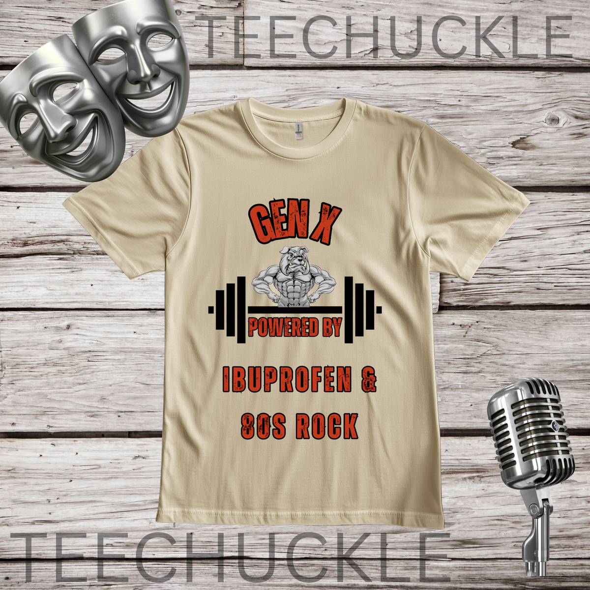A sand graphic t-shirt displayed on a rustic wood background, featuring a design that reads 'GEN X POWERED BY IBUPROFEN & 80S ROCK' with a bulldog cartoon figure lifting a barbell. The shirt is styled with silver comedy masks, a vintage microphone