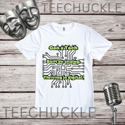 A white short-sleeve graphic T-shirt laid flat on a rustic wood background, with two silver comedy masks, a vintage microphone. The shirt has a circuit board graphic and text that reads "GEN X TECH, BUILT ON ANALOG, THRIVING IN DIGITAL". 