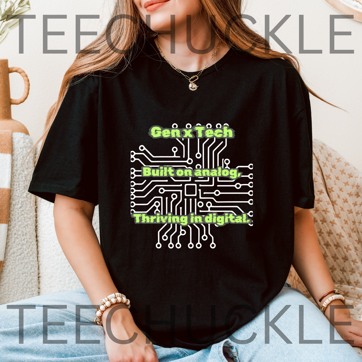 A woman sat wearing a black graphic t-shirt with a white circuit board design and green text reading 'Gen x Tech Built on analog, thriving in digital.