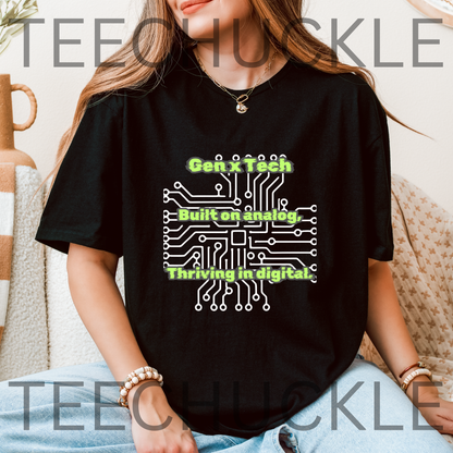 A woman sat wearing a black graphic t-shirt with a white circuit board design and green text reading 'Gen x Tech Built on analog, thriving in digital.