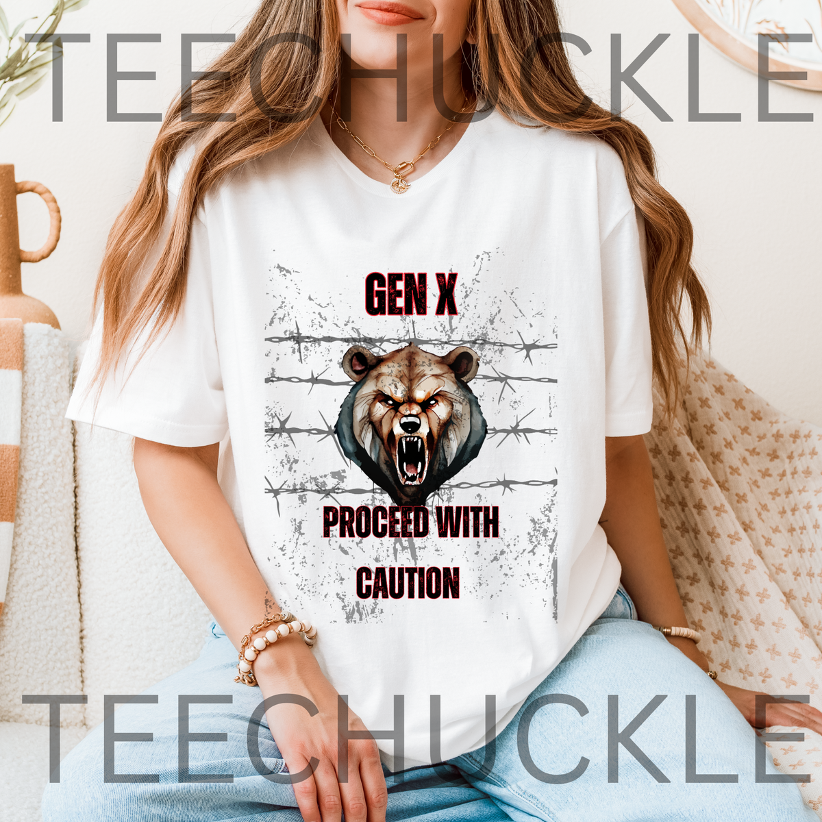 A woman sat on couch wearing a white graphic t-shirt, featuring a roaring bear illustration and the text 'GEN X PROCEED WITH CAUTION'. 