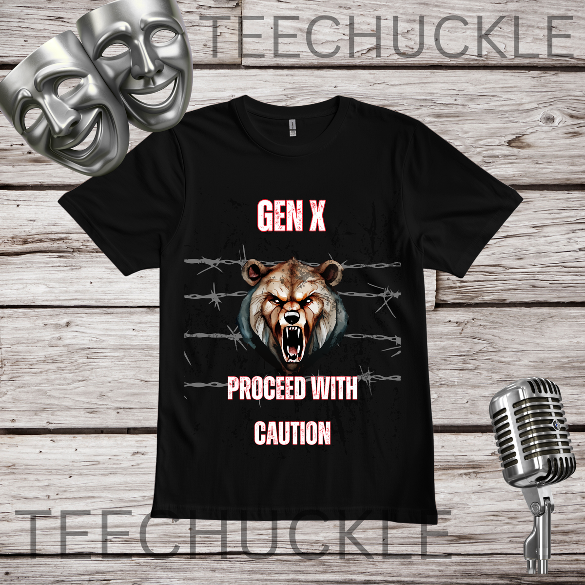 A black graphic t-shirt displayed on a rustic wood background with silver props (a comedy and tragedy mask, a vintage microphone, and a watermark). The shirt features a graphic of a roaring bear behind barbed wire with the text 'GEN X PROCEED WITH CAUTION' in pink and white.