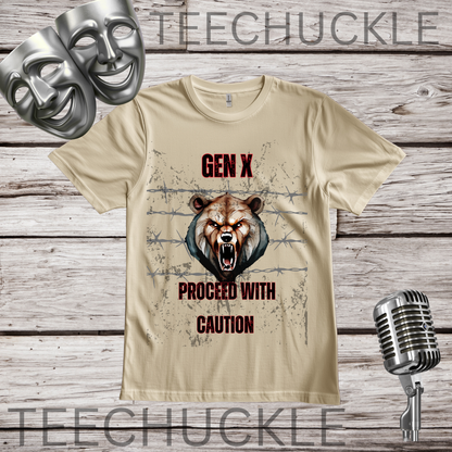 A sand graphic t-shirt featuring a roaring bear head over barbed wire with the text 'GEN X PROCEED WITH CAUTION' in red and black. The t-shirt is displayed on a rustic wood background with decorative props including two silver theater masks, a vintage microphone