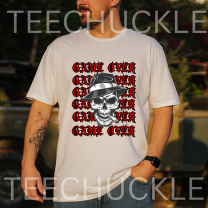 A man wearing a white graphic t-shirt with a 'Game Over' skull design in red and black, set against an outdoor blurred background